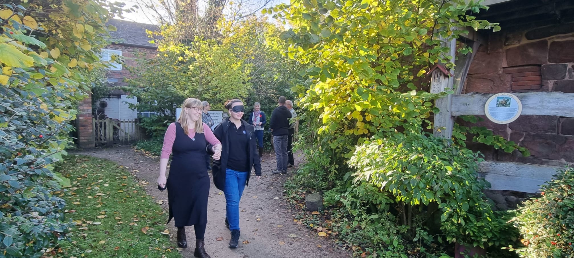 People experiencing visual impairments and sight loss being guided around a garden